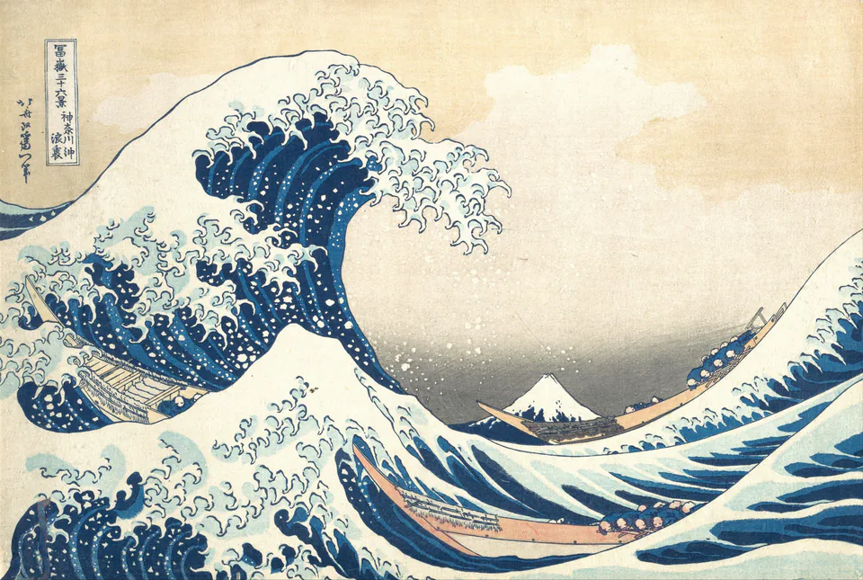 Woodblock print: a towering blue wave curls over three long boats, its crest breaking into claw-like foam; Mount Fuji, small and snow-capped, sits in the distance.